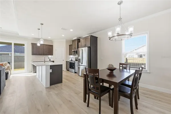 a view of a dining room and livingroom with furniture wooden floor a chandelier
