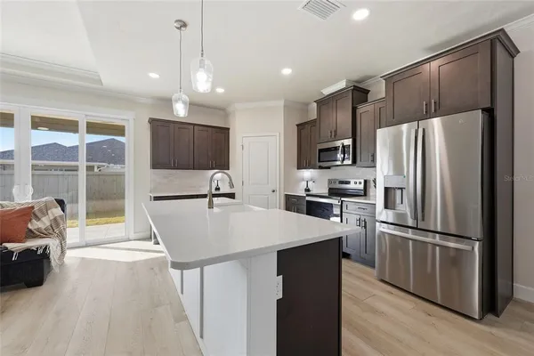 a large kitchen with kitchen island a large counter top space a sink stainless steel appliances and cabinets