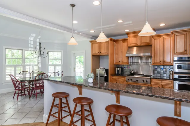 a kitchen with stainless steel appliances granite countertop a stove a kitchen island a dining table and chairs