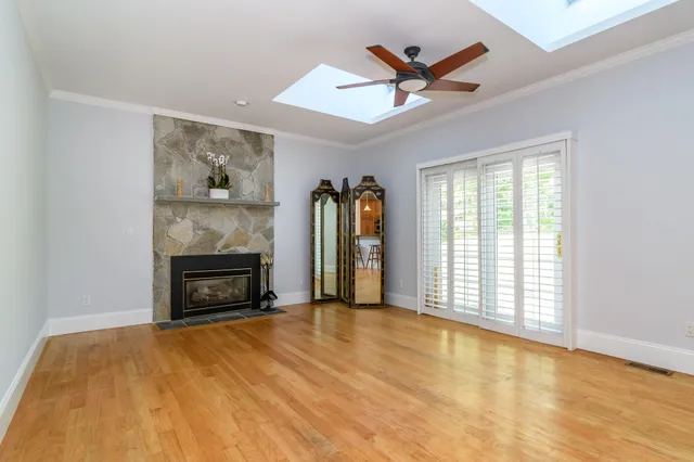 a living room with a fireplace furniture a ceiling fan and a large window