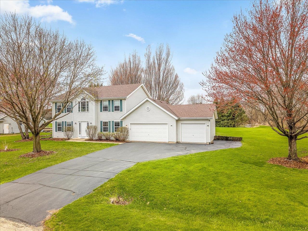 8027 Barclay Road Rockford, IL 61102 - Photo 2 of 67 a front view of a house with a garden and trees