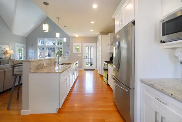 a large kitchen with kitchen island a large counter top space a sink stainless steel appliances and cabinets