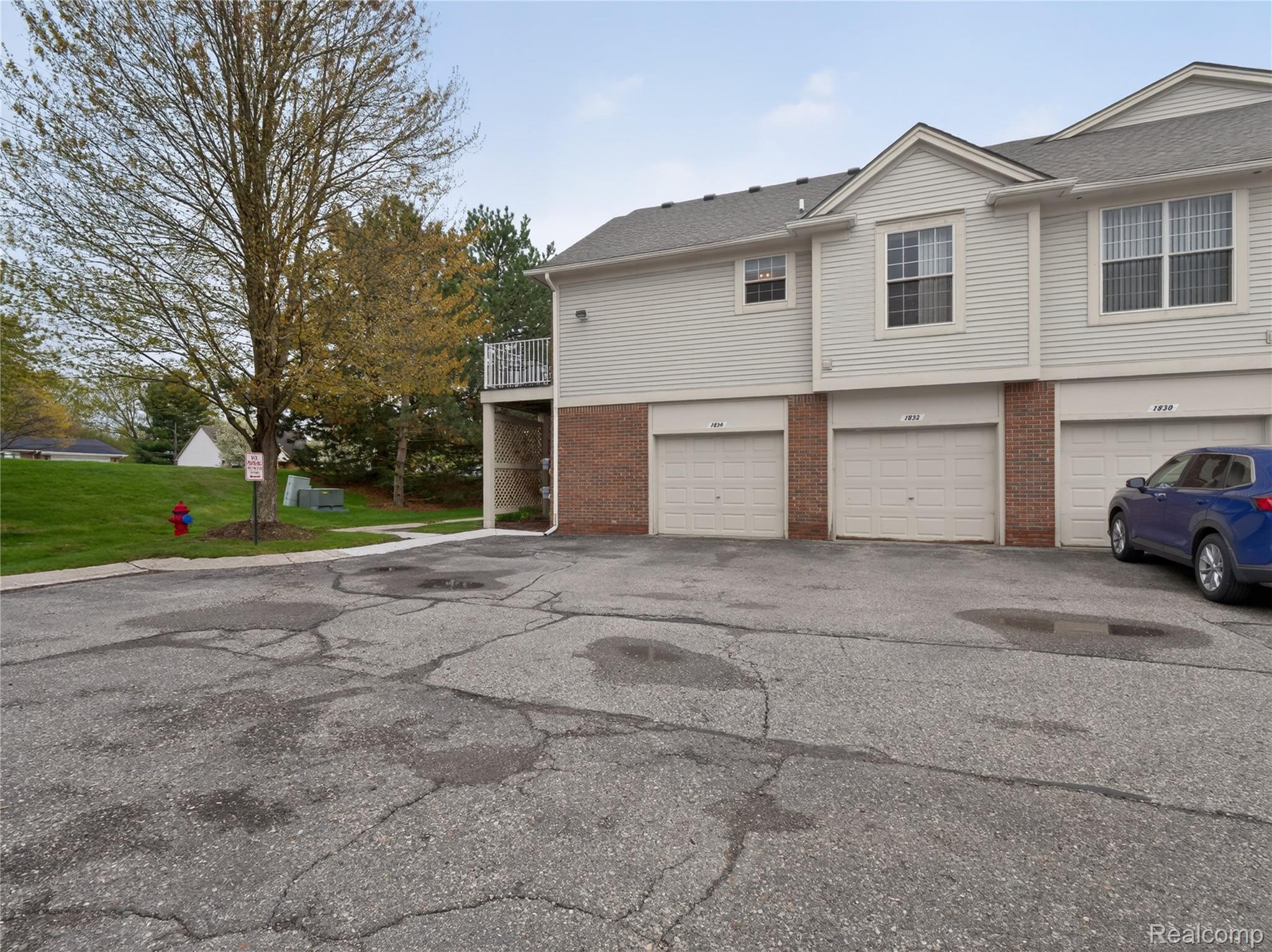 1834 Flagstone Circle, Unit 37 Rochester, MI 48307 - Photo 26 of 31 View of property exterior with an attached garage, brick siding, driveway, a balcony, and roof with shingles