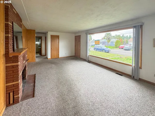 a view of an empty room with a fireplace and a large window
