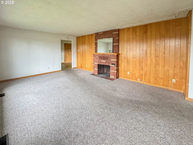 a view of an empty room with a fireplace and a window