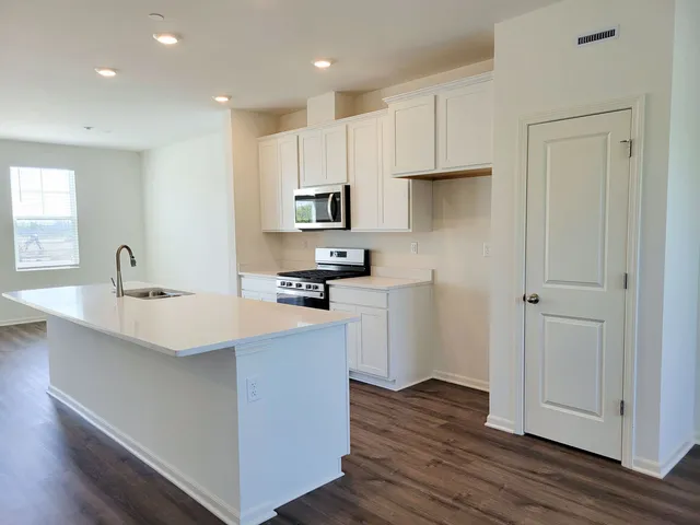 a kitchen with stainless steel appliances a sink a stove a refrigerator and cabinets
