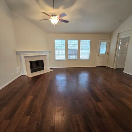 a view of an empty room with wooden floor fireplace and a window