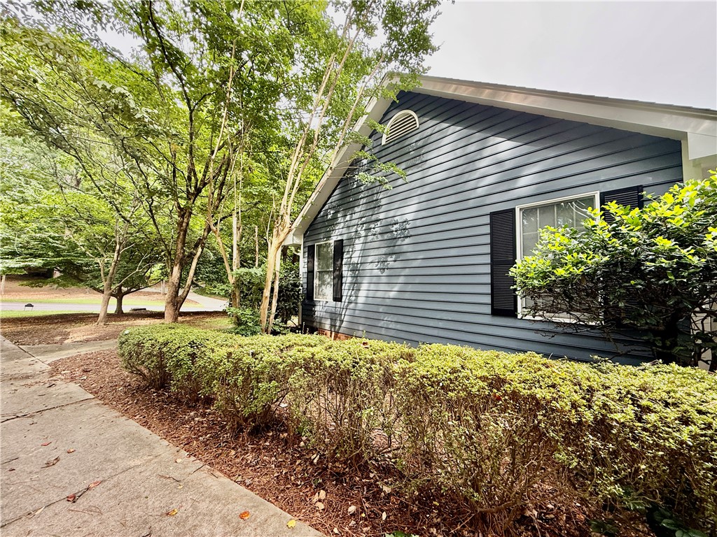 235 Stonehaven Way Seneca, SC 29672 - Photo 12 of 35 A charming residence with deep blue siding is nestled among mature trees, enhancing its inviting curb appeal.