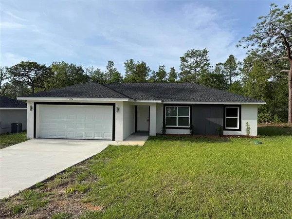 a front view of house with yard and trees in the background