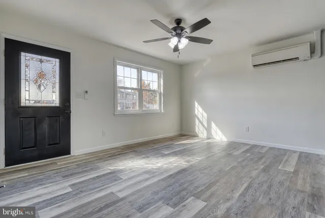 a view of an empty room with wooden floor and a window