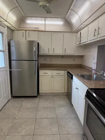 a kitchen with a refrigerator sink and cabinets