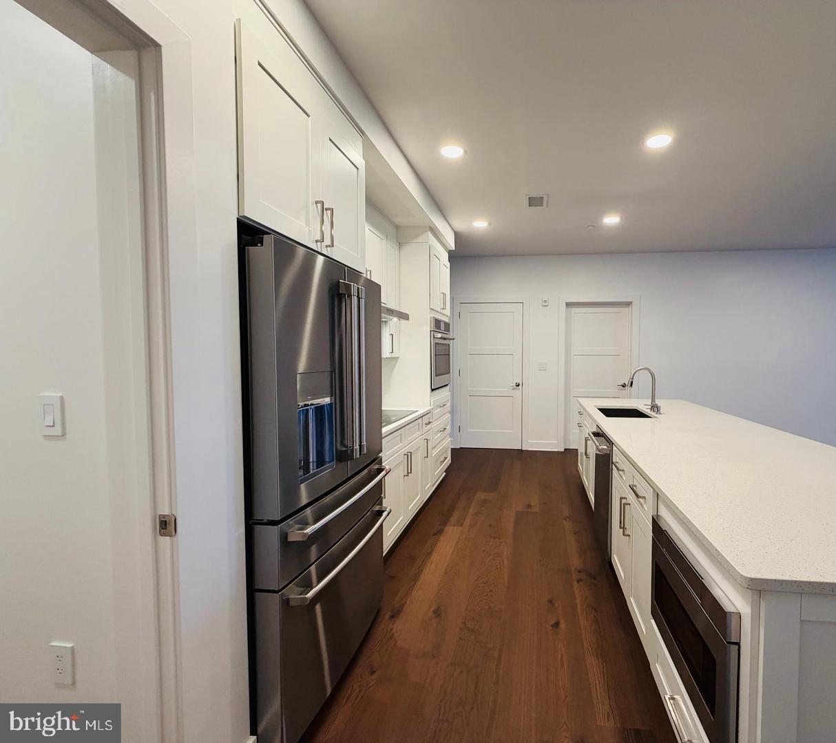 208 2nd Street East, Unit 202 Frederick, MD 21701 - Photo 5 of 9 a kitchen with a refrigerator and white cabinets