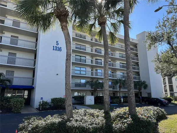a front view of multi story residential apartment building with yard and sign board