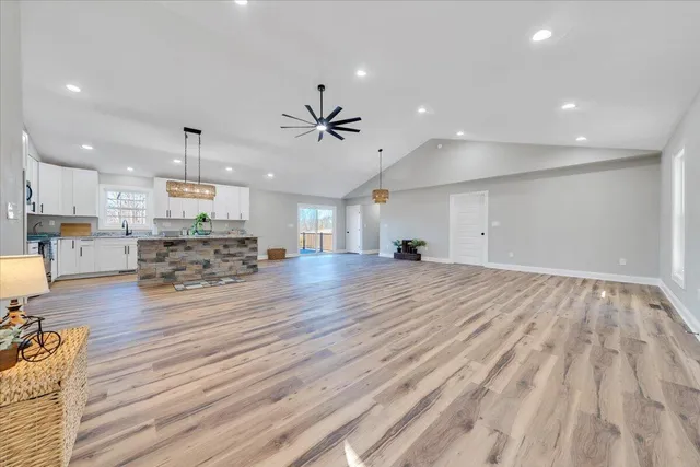 an empty room with kitchen view and wooden floor