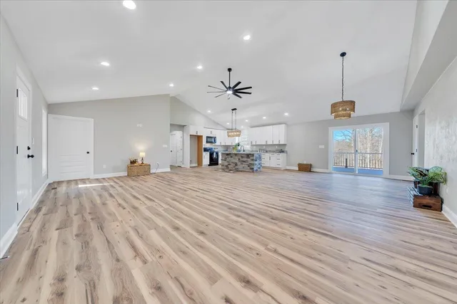 a large kitchen with kitchen island wooden floors white cabinets and stainless steel appliances