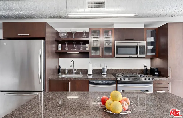 a kitchen with stainless steel appliances granite countertop a refrigerator a stove and a sink