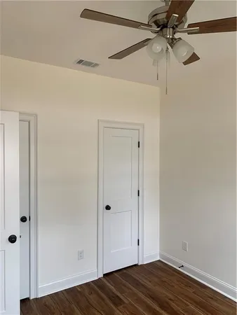 an empty room with wooden floor chandelier fan and windows