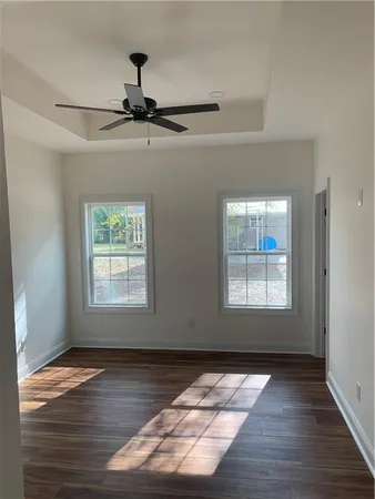 a view of a hallway with wooden floor and a bathroom