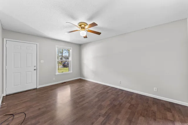 a view of an empty room with a window and wooden floor