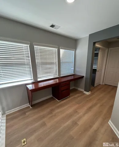 a view of an empty room with a window and wooden floor
