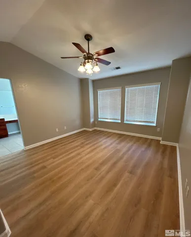 a view of an empty room with window and chandelier fan