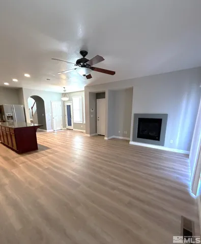 a view of a livingroom with a fireplace a ceiling fan and wooden floor