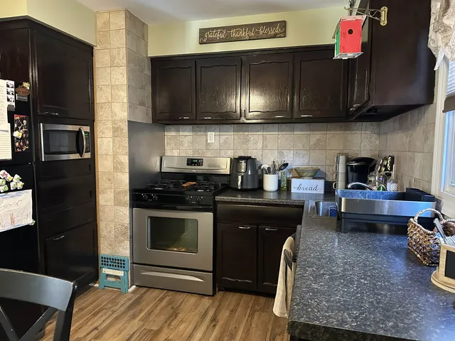 a kitchen with stainless steel appliances kitchen island granite countertop a stove refrigerator and microwave