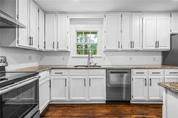 a kitchen with granite countertop white cabinets and a stove