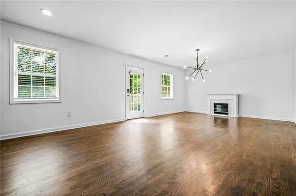 an empty room with wooden floor windows and ceiling fan