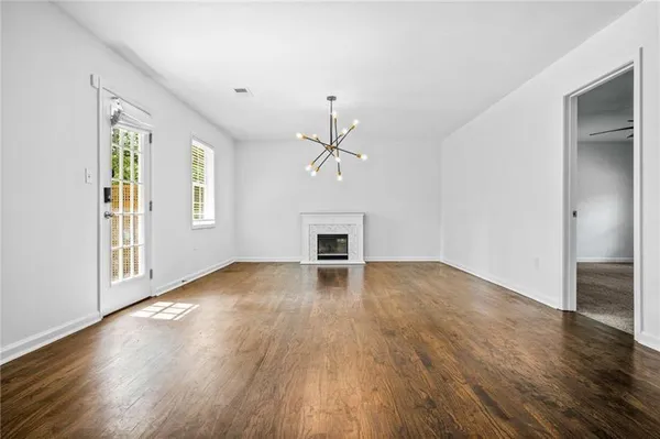 an empty room with wooden floor windows and fireplace