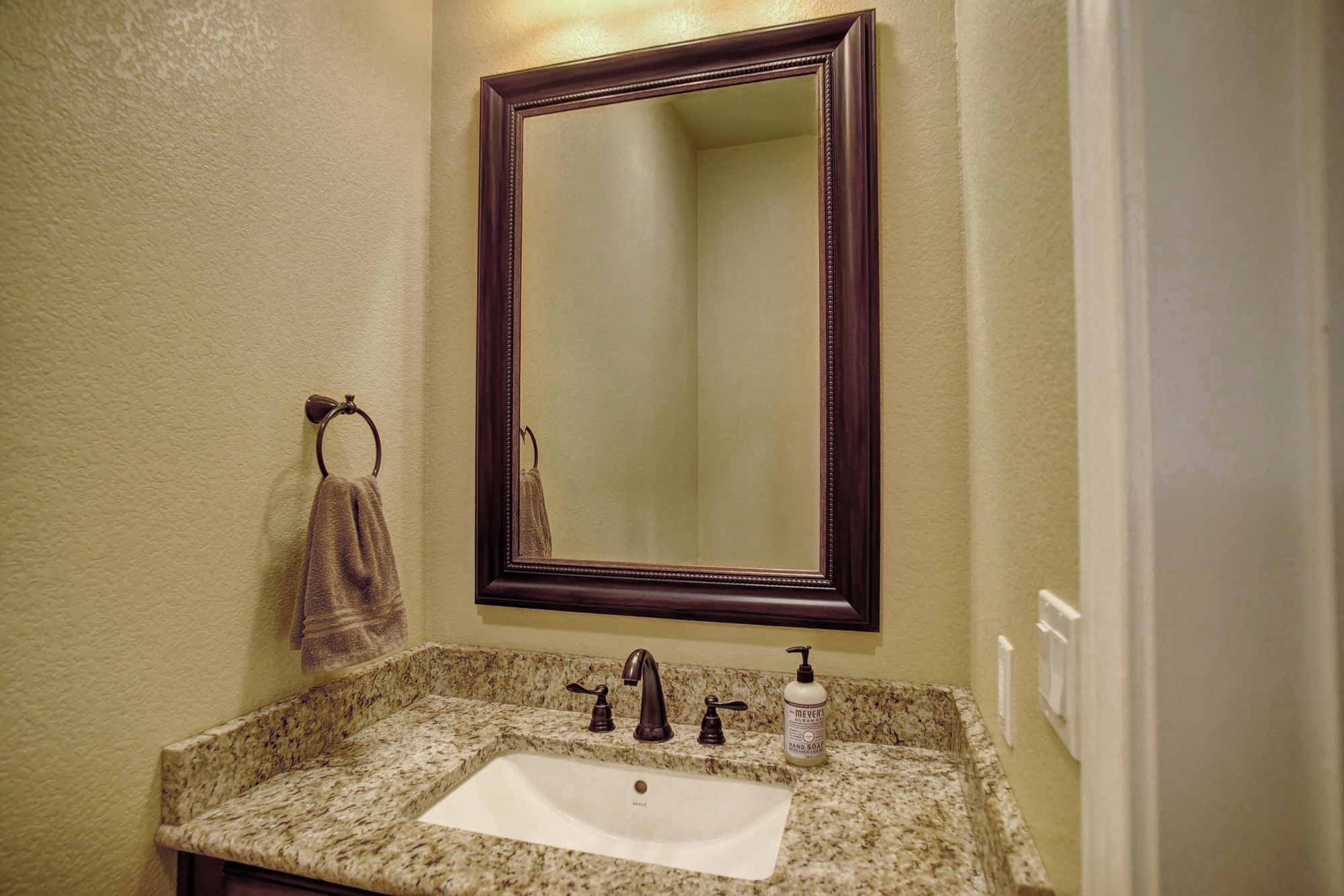 115 Pine Point Cove Elgin, TX 78621 - Photo 30 of 39 A well-appointed bathroom vanity features a broad granite counter with an undermount sink and a framed mirror.