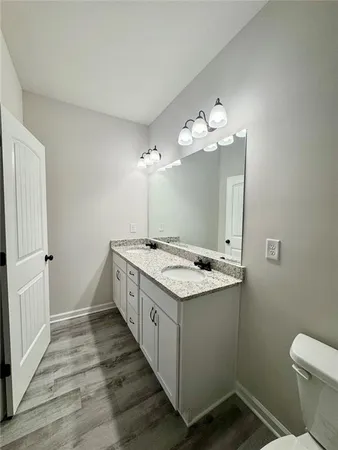 a spacious bathroom with a granite countertop sink a toilet and a mirror