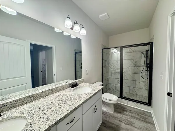 a bathroom with a granite countertop sink a toilet and shower