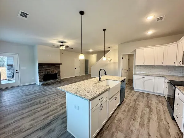 a large kitchen with kitchen island a stove a sink a center island and wooden floor