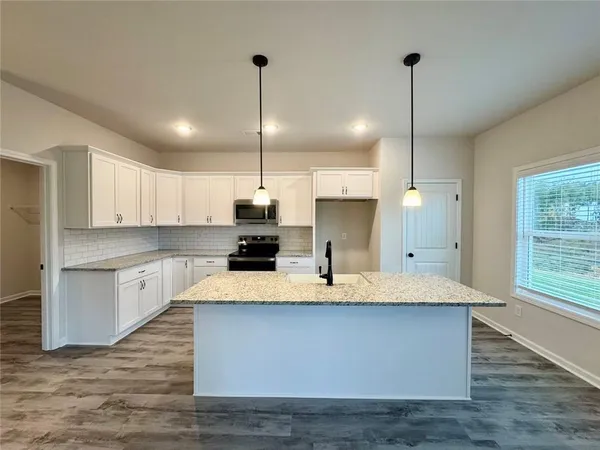 a kitchen with kitchen island white cabinets counter space and a sink