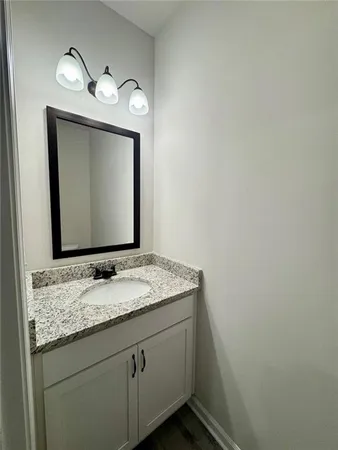 a bathroom with a granite countertop sink vanity and mirror
