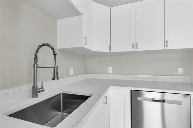 a kitchen with granite countertop white cabinets and a sink