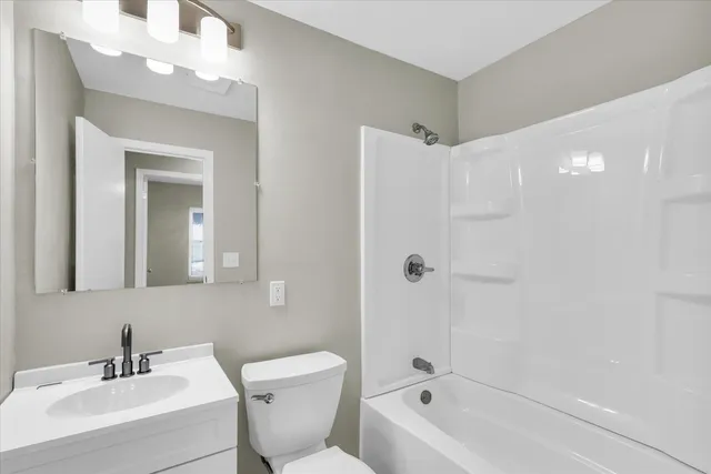 a bathroom with a bathtub shower sink vanity and toilet