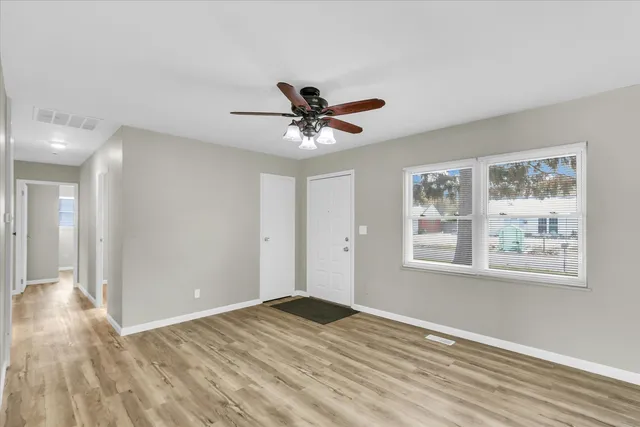 a view of empty room with wooden floor and fan