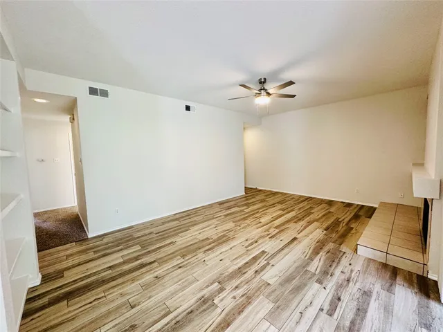a view of a room with wooden floor and a ceiling fan