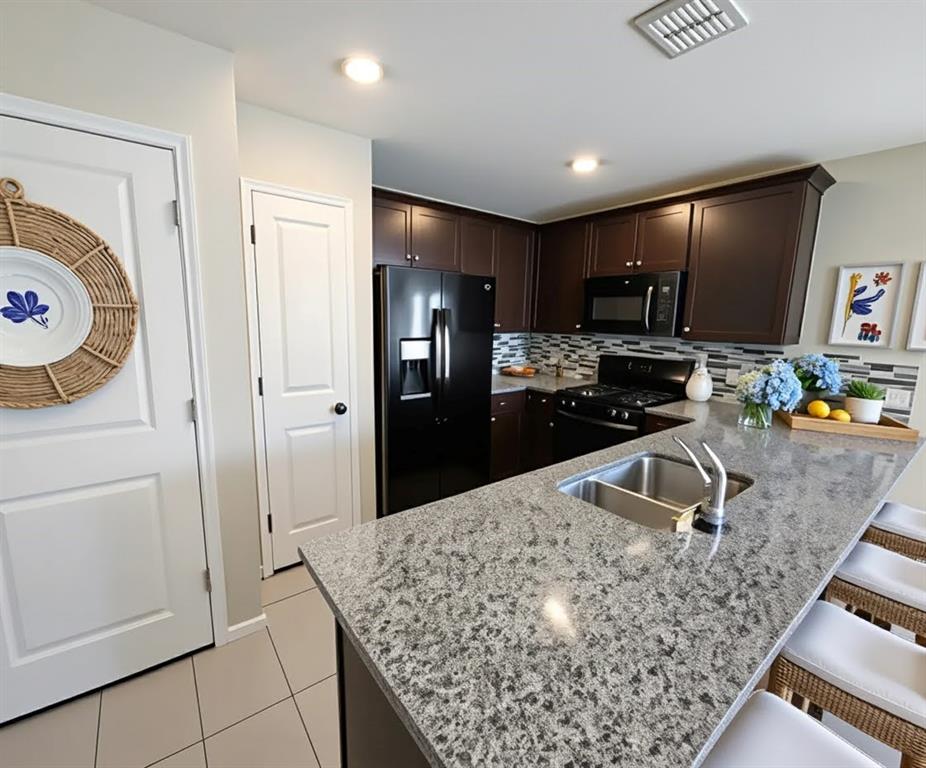 6087 Determine Lane Forney, TX 75126 - Photo 8 of 14 Kitchen with dark wood finish cabinets, a peninsula, a kitchen breakfast bar, black appliances, and tasteful backsplash