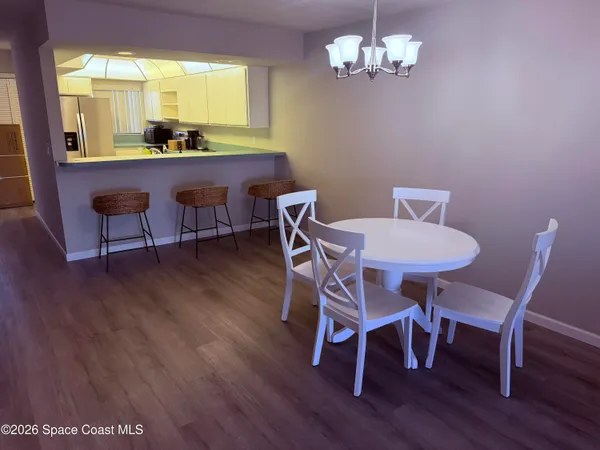 a view of a dining room with furniture a chandelier and wooden floor