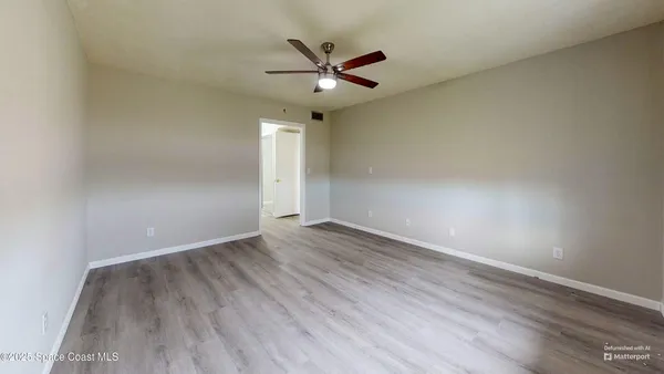 an empty room with wooden floor and ceiling fan