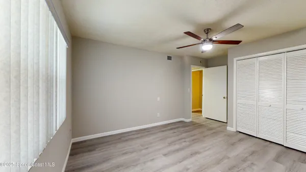 an empty room with wooden floor fan and windows