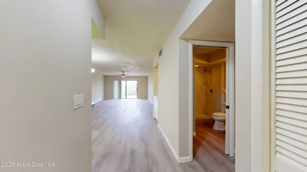 an empty room with wooden floor fan and windows