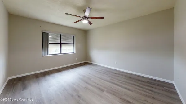 an empty room with wooden floor and ceiling fan