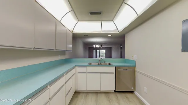 a view of a kitchen with a sink and dishwasher with wooden floor