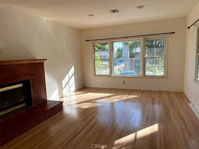 a view of empty room with wooden floor and fireplace