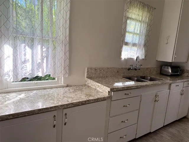a kitchen with granite countertop white cabinets and a window