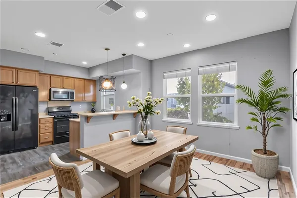 a kitchen with stainless steel appliances granite countertop a refrigerator a sink dishwasher a stove and white countertops with wooden floor